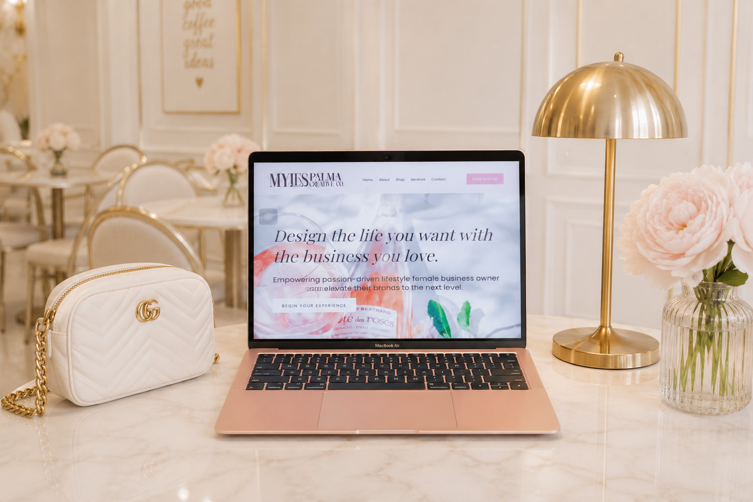 A laptop showing the Myles Palma Creative Co. website on a marble café table